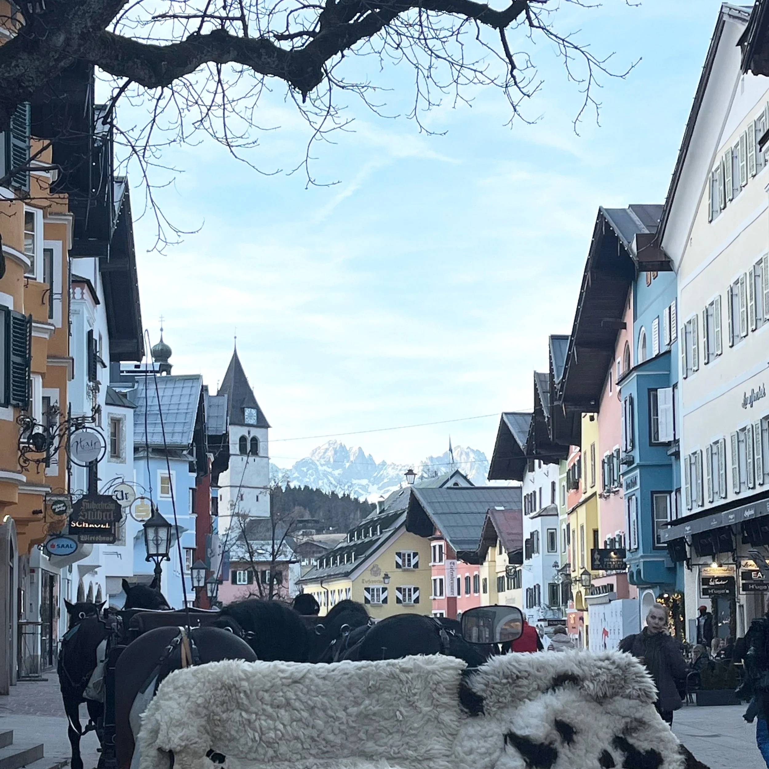 A horsedrawn carriage in Kitzbühel, Austria, with a view of the mountains in the background.