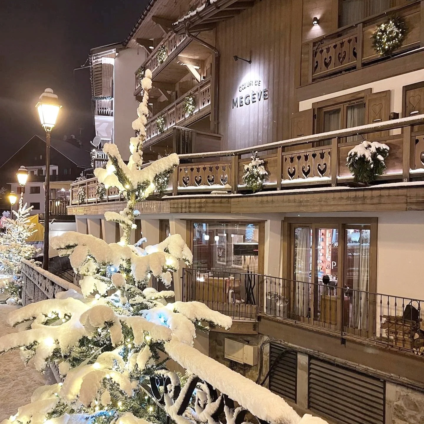 A snow covered tree outside of a hotel in Mègeve, France.