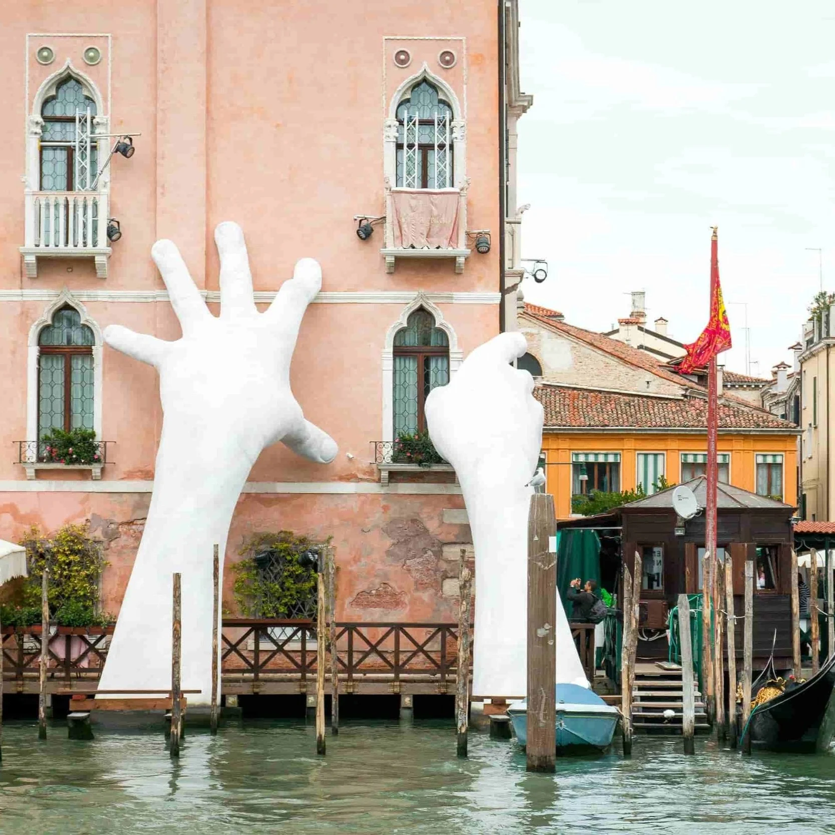 Lorenzo Quinn's sculpture "Support", two hands reaching out of the canal to hold up a Venetian building.
