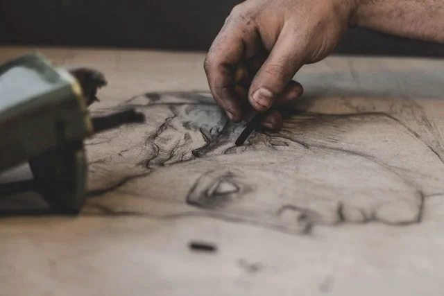 A hand sketching with charcoal.