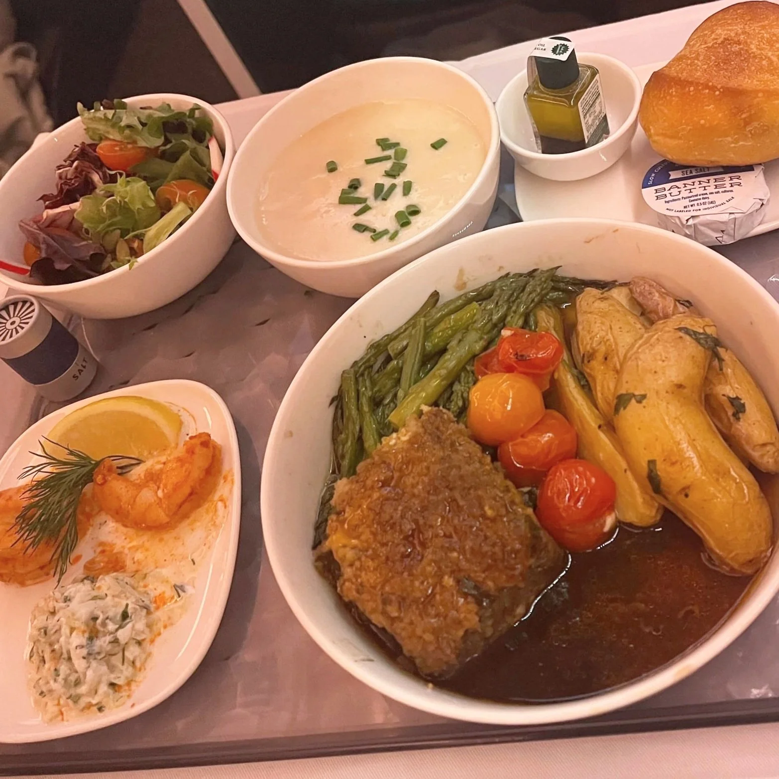 A Delta One meal with roasted chicken, soup, salad, and bread.