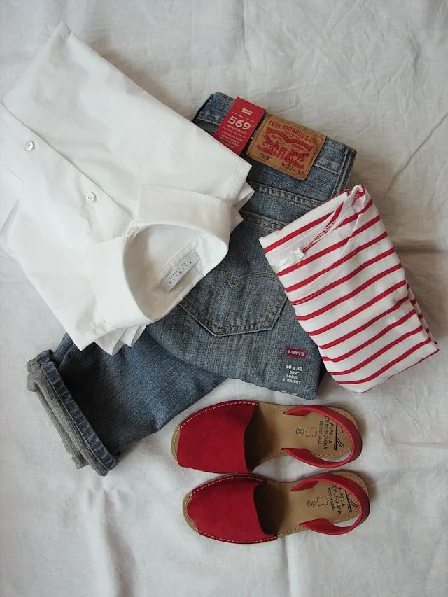 An outfit of jeans, a top, and shoes are arranged.