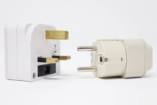An EU and UK electronic converter plug sitting side by side.