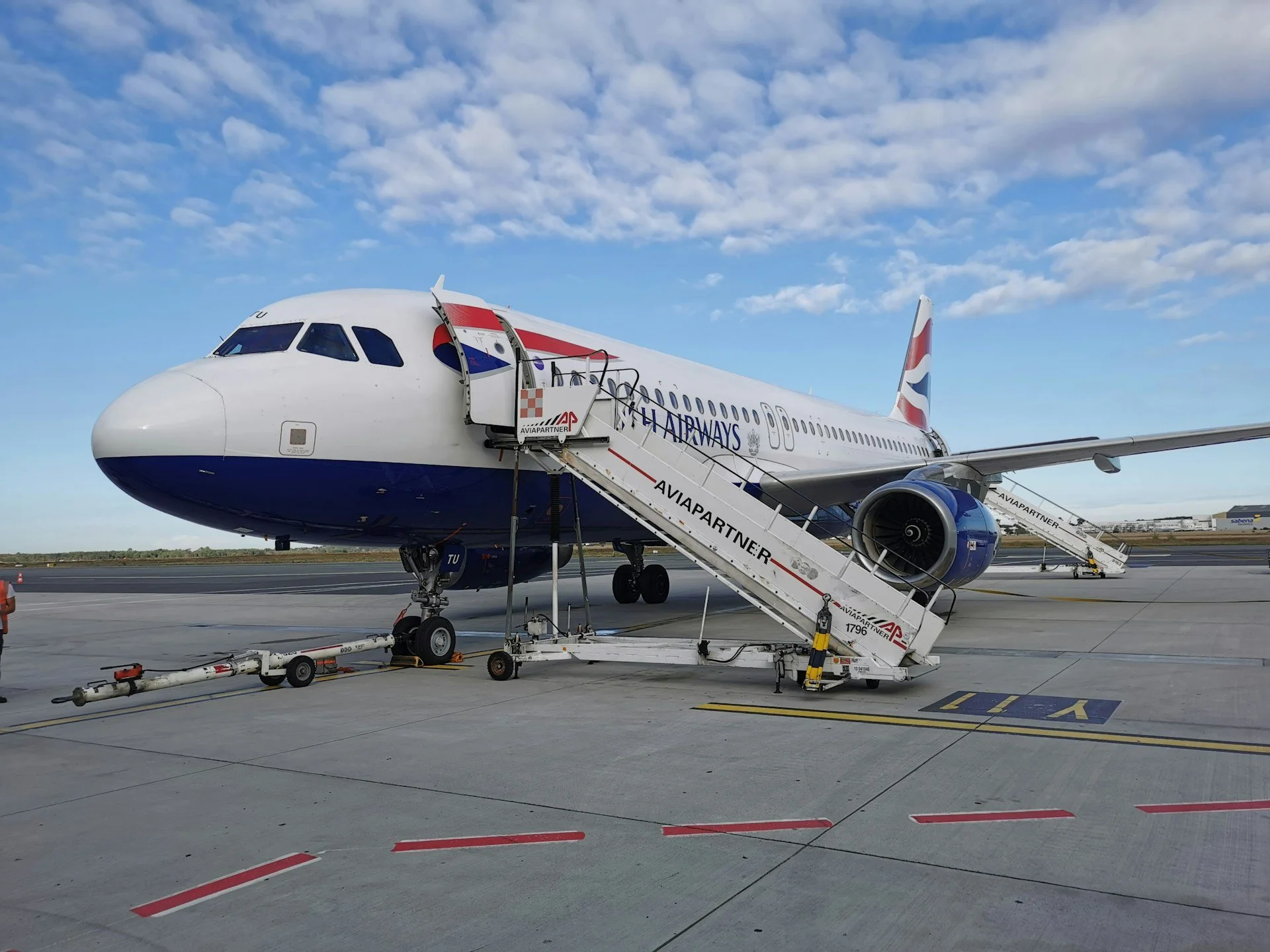 A British Airways plane sits on the tarmac with its doors open, ready for boarding.