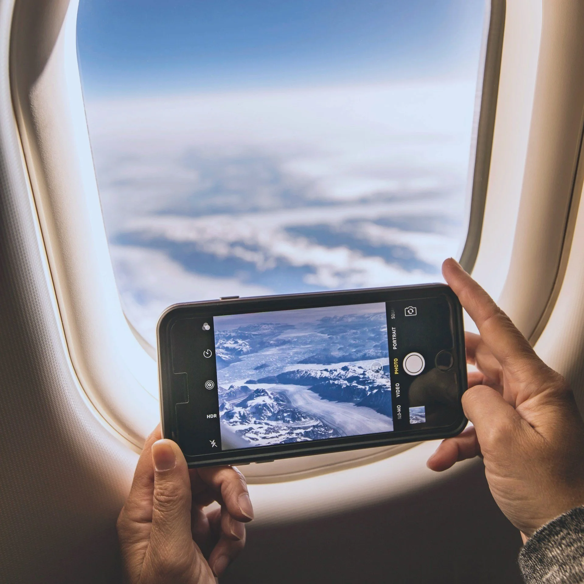 An iPhone taking a photo out the window of a plane.