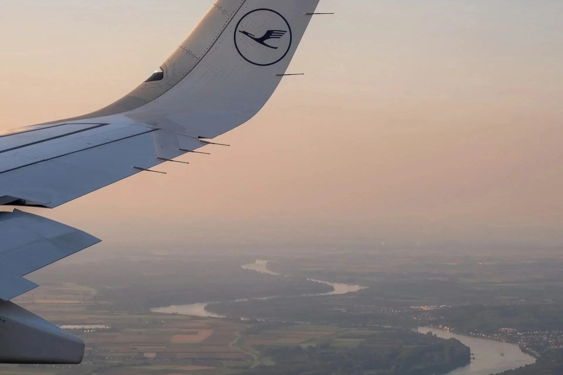 The wing of a Lufthansa plane over the winding Main River.