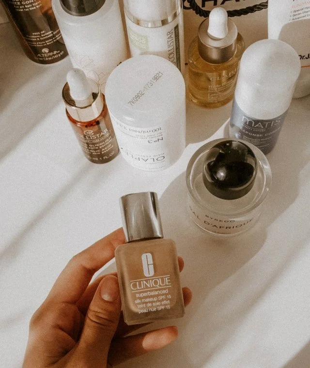 A hand holding a bottle of foundation.